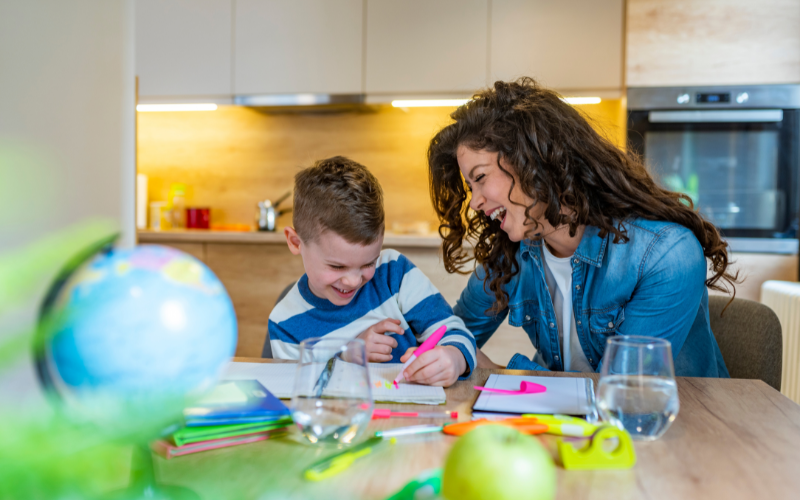 Mother and son laughing together while working on homework