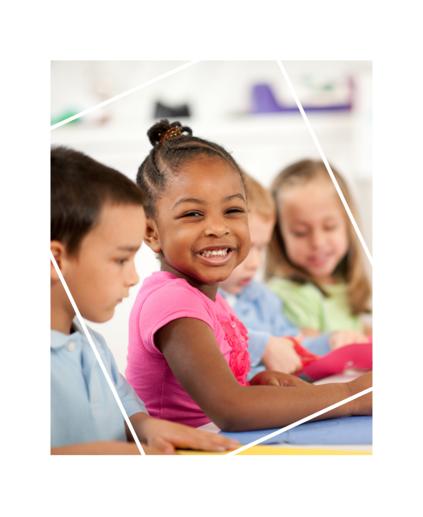 Young girl in classroom smiling at the camera