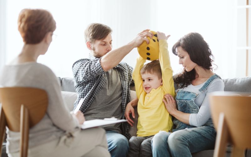 Family with young child speaking with therapist